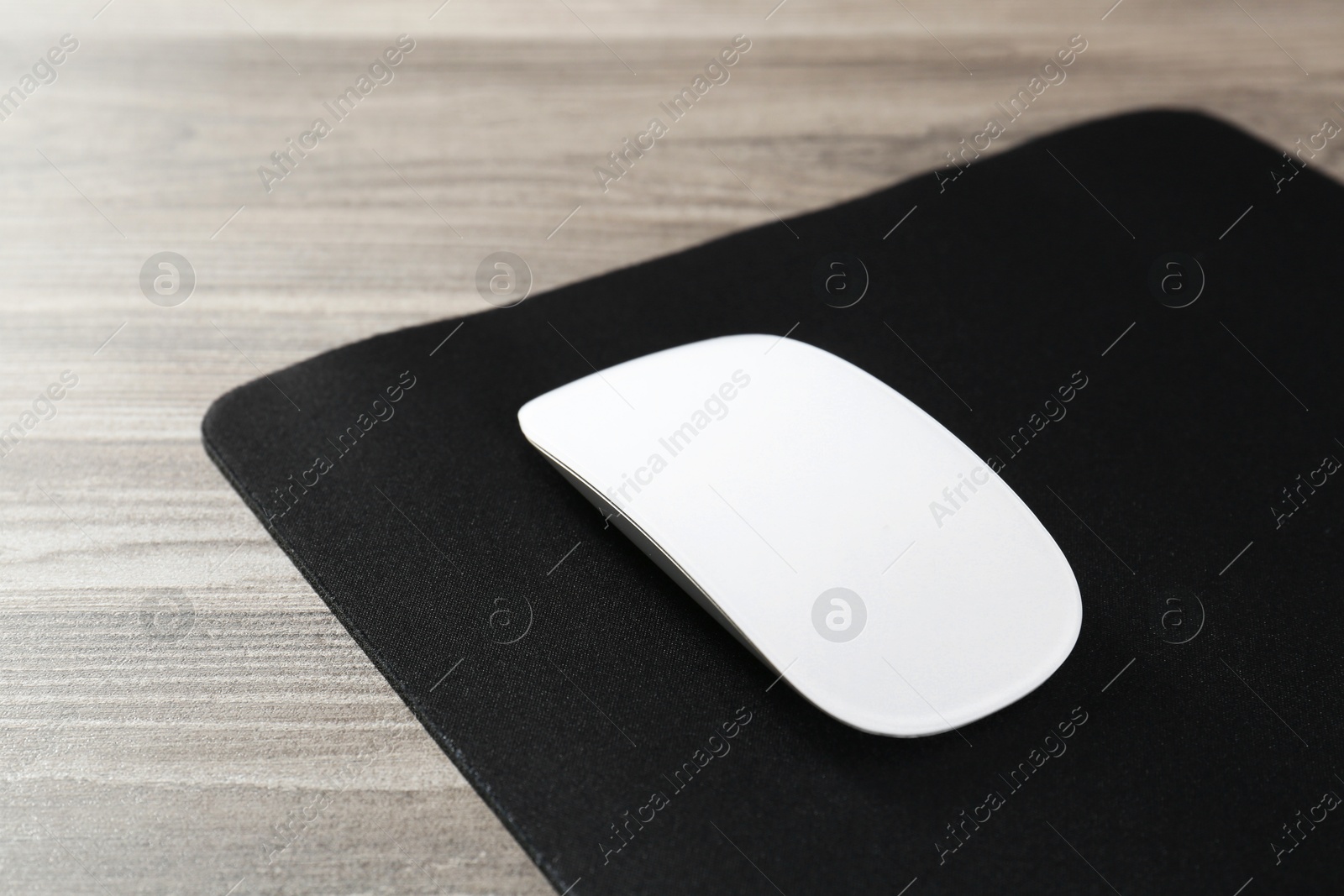 Photo of Wireless mouse and mousepad on wooden table