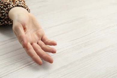 Chiromancy and foretelling. Woman showing palm at white wooden table, top view. Space for text