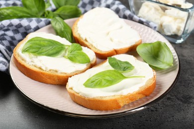 Delicious sandwiches with cream cheese and basil leaves on grey table, closeup