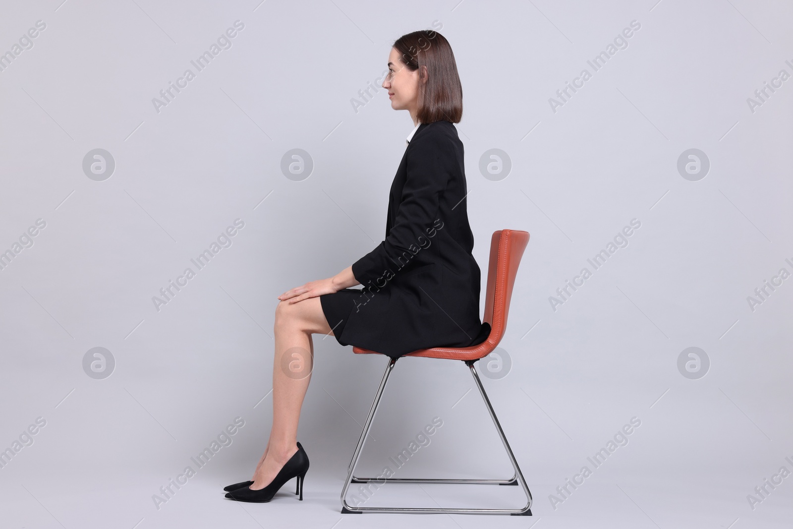 Photo of Woman with good posture sitting on chair against gray background