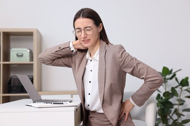 Woman suffering from neck pain in office. Symptom of poor posture