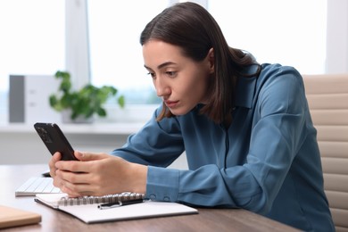 Woman with poor posture using smartphone in office