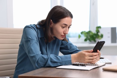 Woman with poor posture using smartphone in office