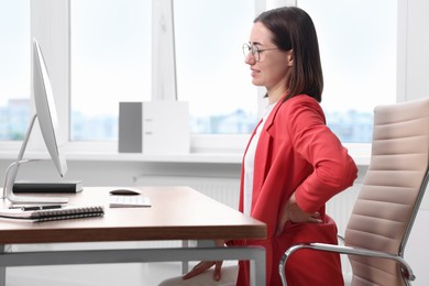 Photo of Woman suffering from back pain in office. Symptom of poor posture