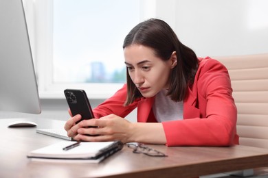 Woman with poor posture using smartphone in office