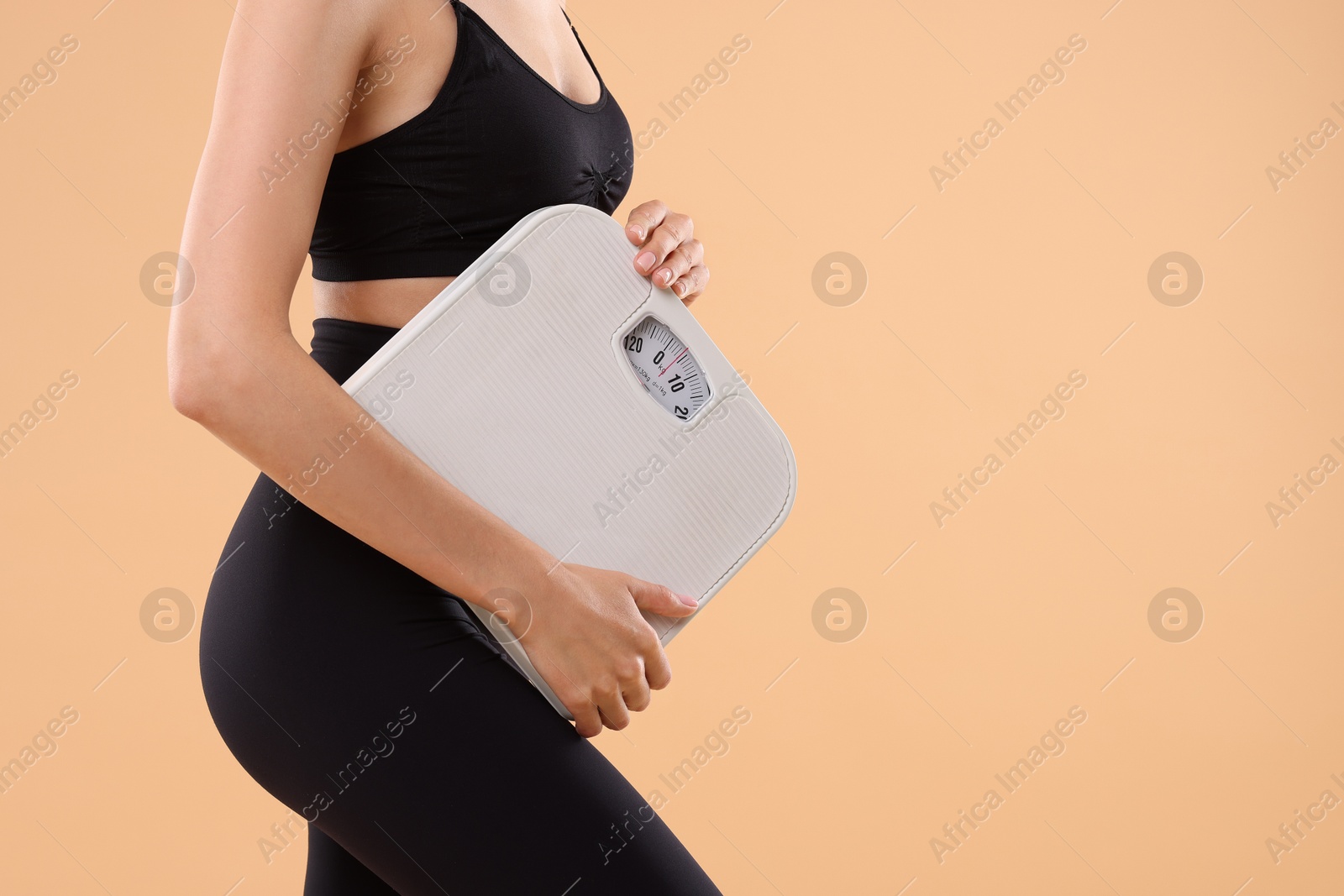 Photo of Diet and weight loss concept. Woman with floor scale on beige background, closeup. Space for text