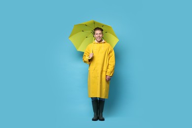 Photo of Young man with yellow umbrella on light blue background
