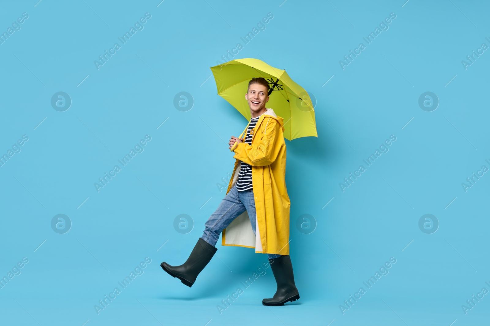 Photo of Young man with yellow umbrella on light blue background