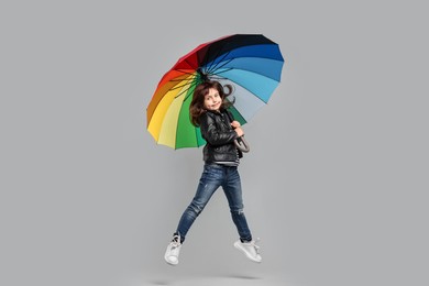 Photo of Cute little girl with colorful umbrella on light grey background