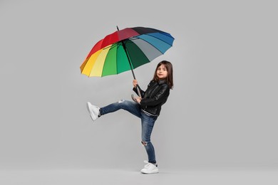 Photo of Cute little girl with colorful umbrella on light grey background