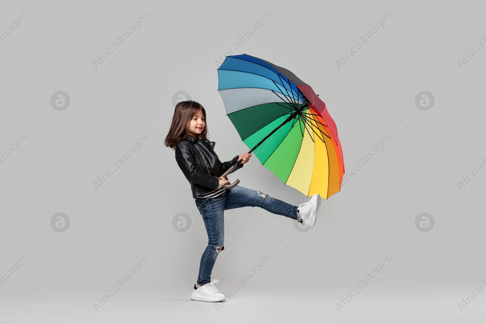 Photo of Cute little girl with colorful umbrella on light grey background