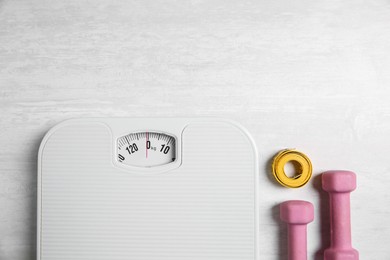 Photo of Bathroom scale, measuring tape and dumbbells on white wooden background, flat lay. Space for text