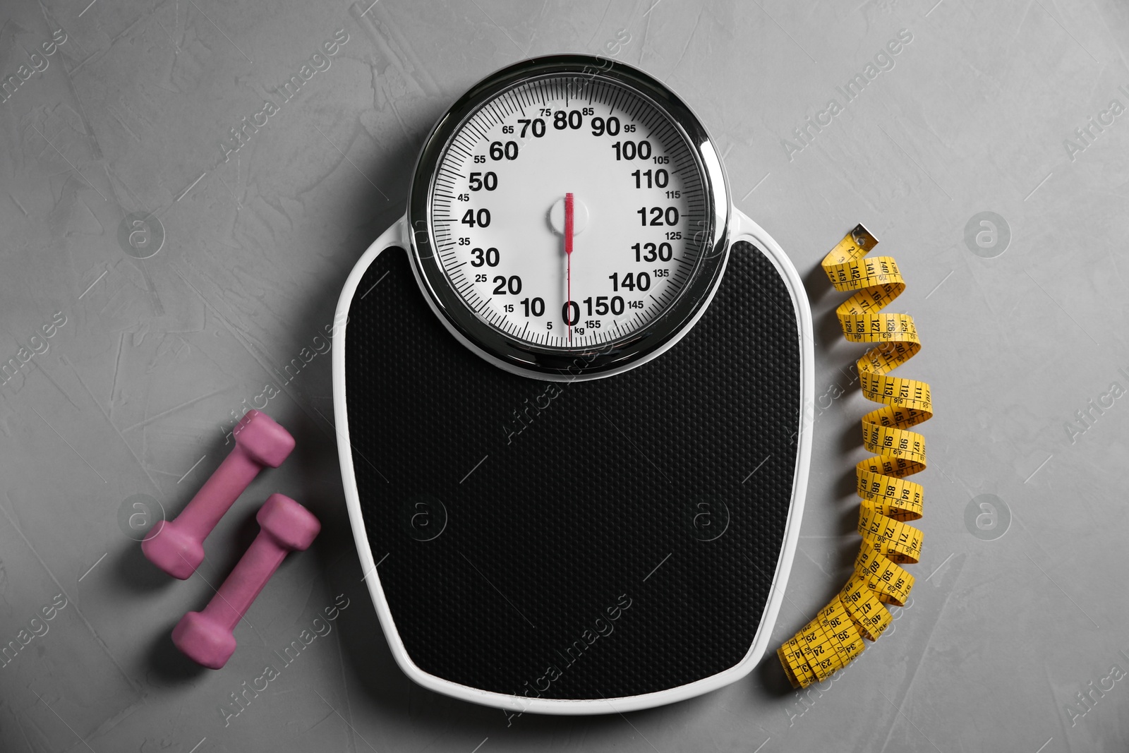 Photo of Bathroom scale, measuring tape and dumbbells on grey textured background, flat lay