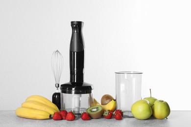 Photo of Hand blender kit, fresh fruits and strawberries on gray table against white background