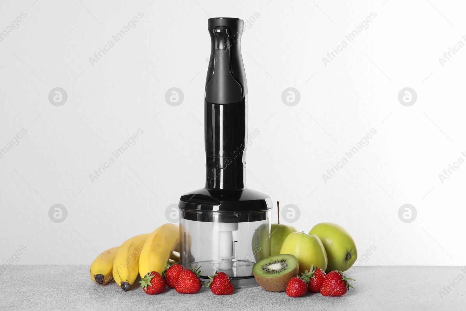 Photo of Hand blender kit, fresh fruits and strawberries on gray table against white background