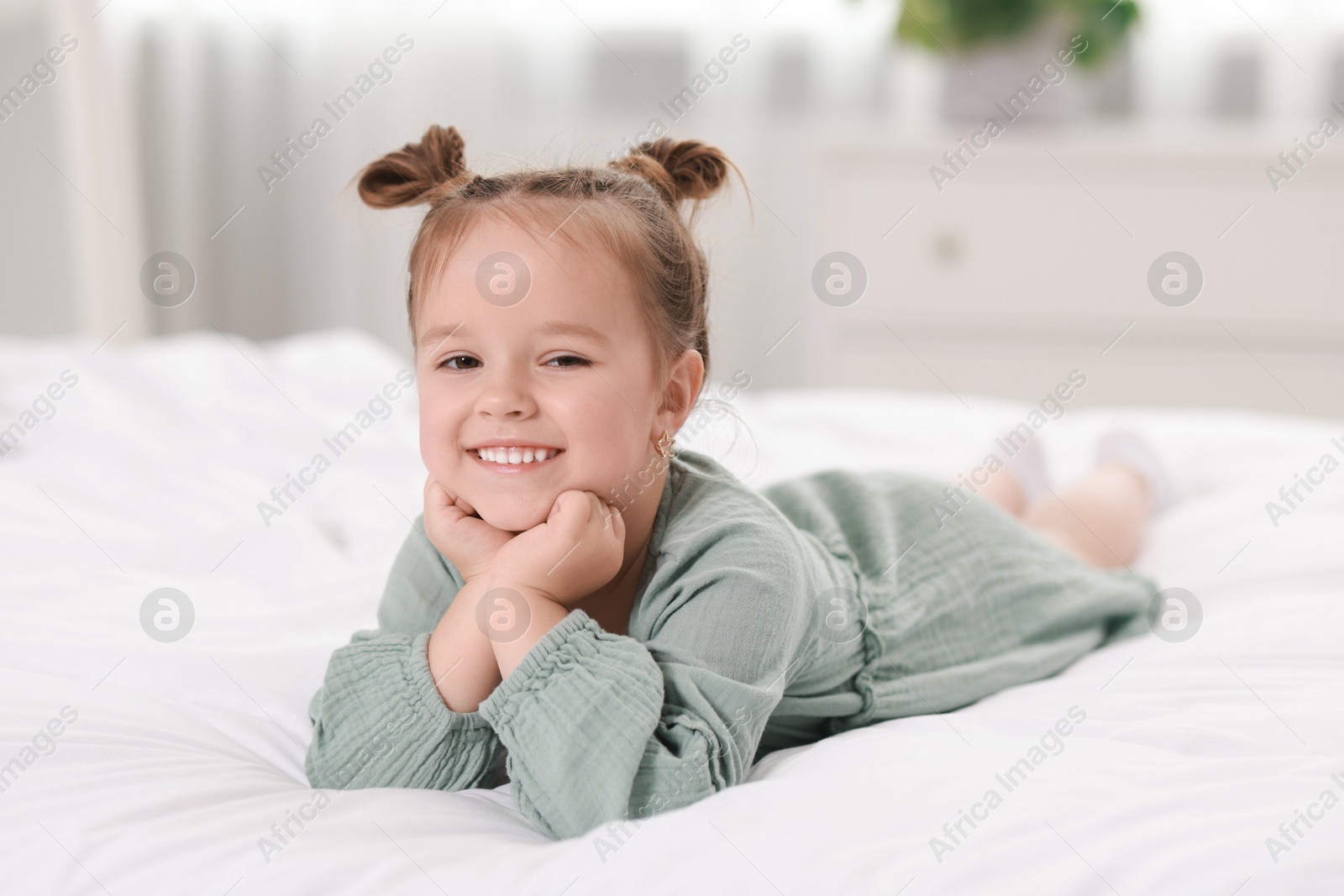 Photo of Portrait of happy little girl on bed at home