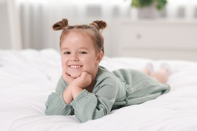 Portrait of happy little girl on bed at home