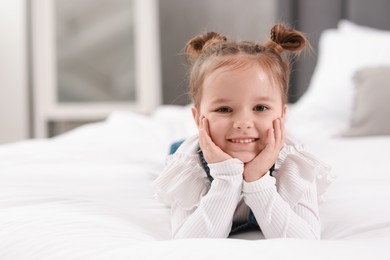 Photo of Portrait of happy little girl on bed indoors, space for text