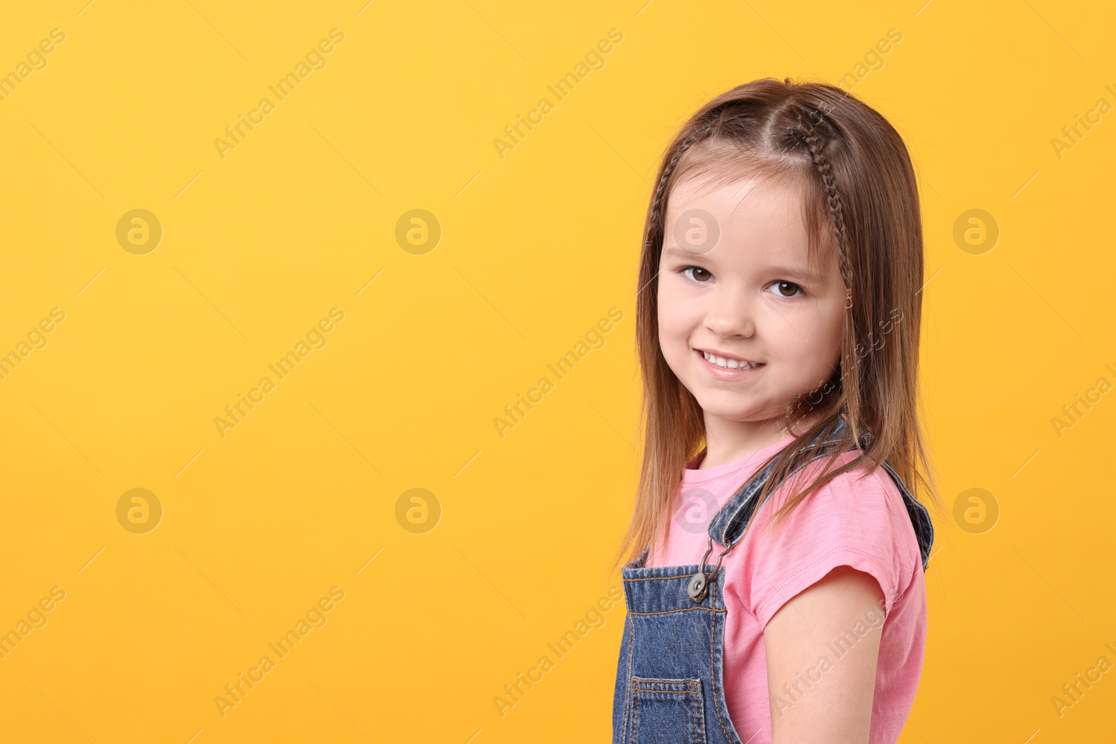 Photo of Portrait of happy little girl on orange background, space for text