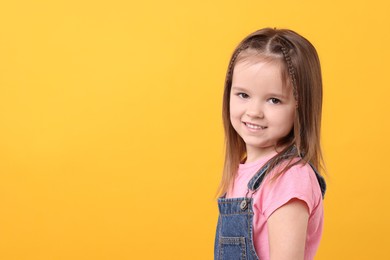 Portrait of happy little girl on orange background, space for text