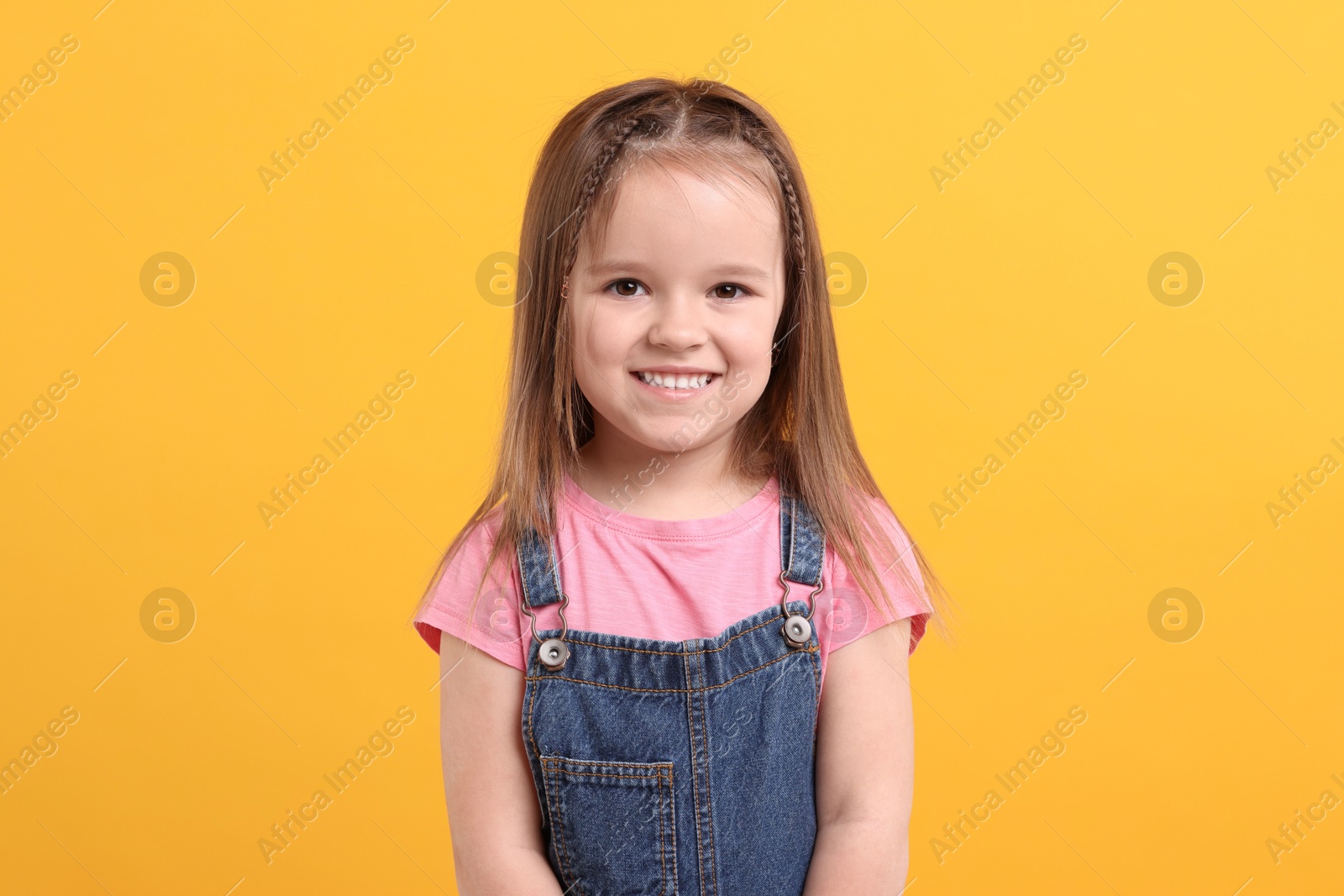 Photo of Portrait of happy little girl on orange background