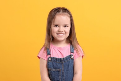 Photo of Portrait of happy little girl on orange background