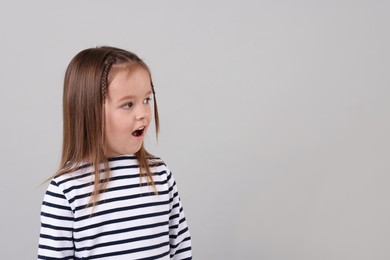 Photo of Portrait of emotional little girl on grey background, space for text