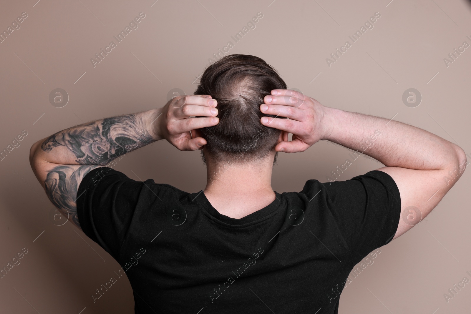 Photo of Baldness concept. Man with bald spot on beige background, back view