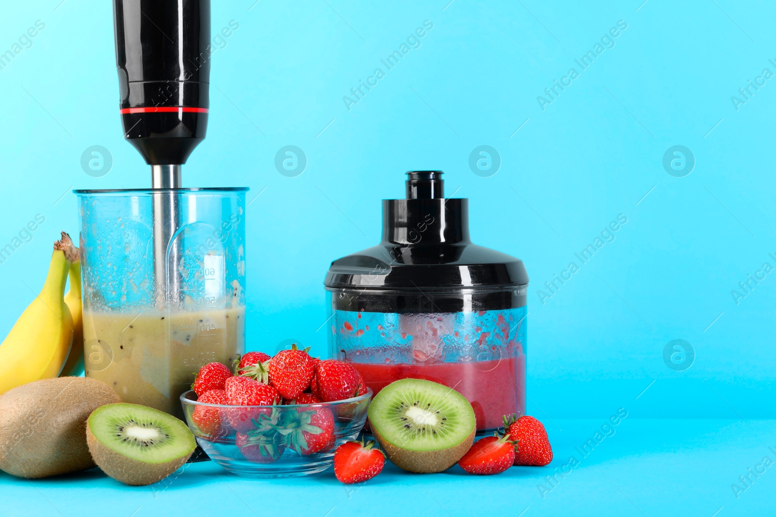 Photo of Hand blender kit, mixtures of ingredients and fresh fruits on light blue background. Space for text