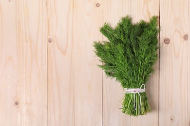 Bunch of fresh green dill on wooden table, top view. Space for text