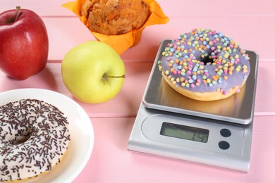 Photo of Kitchen scale with donut and other products on pink wooden table