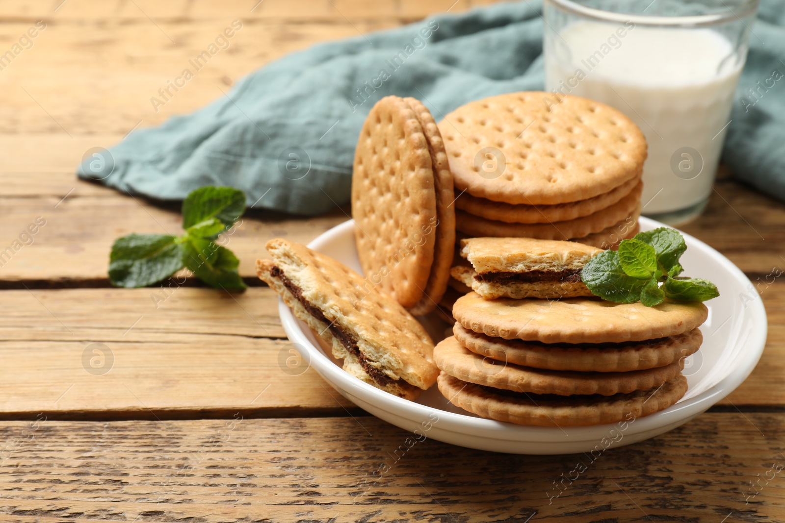 Photo of Tasty sandwich cookies and glass of milk on wooden table, closeup