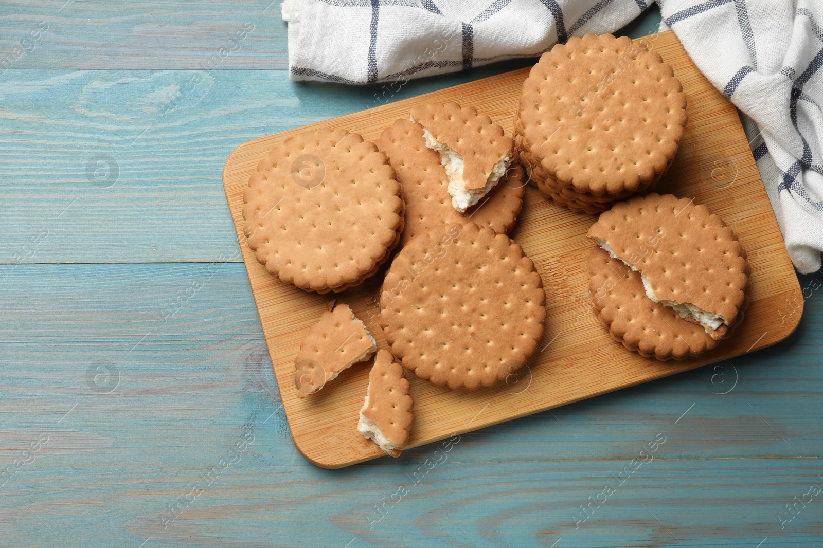 Photo of Tasty sandwich cookies on light blue wooden table, above view. Space for text