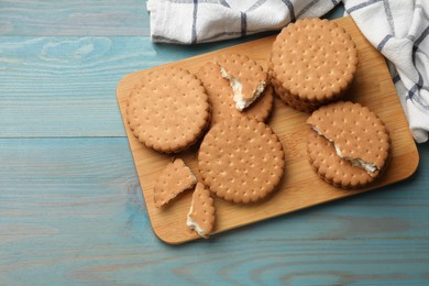 Tasty sandwich cookies on light blue wooden table, above view. Space for text