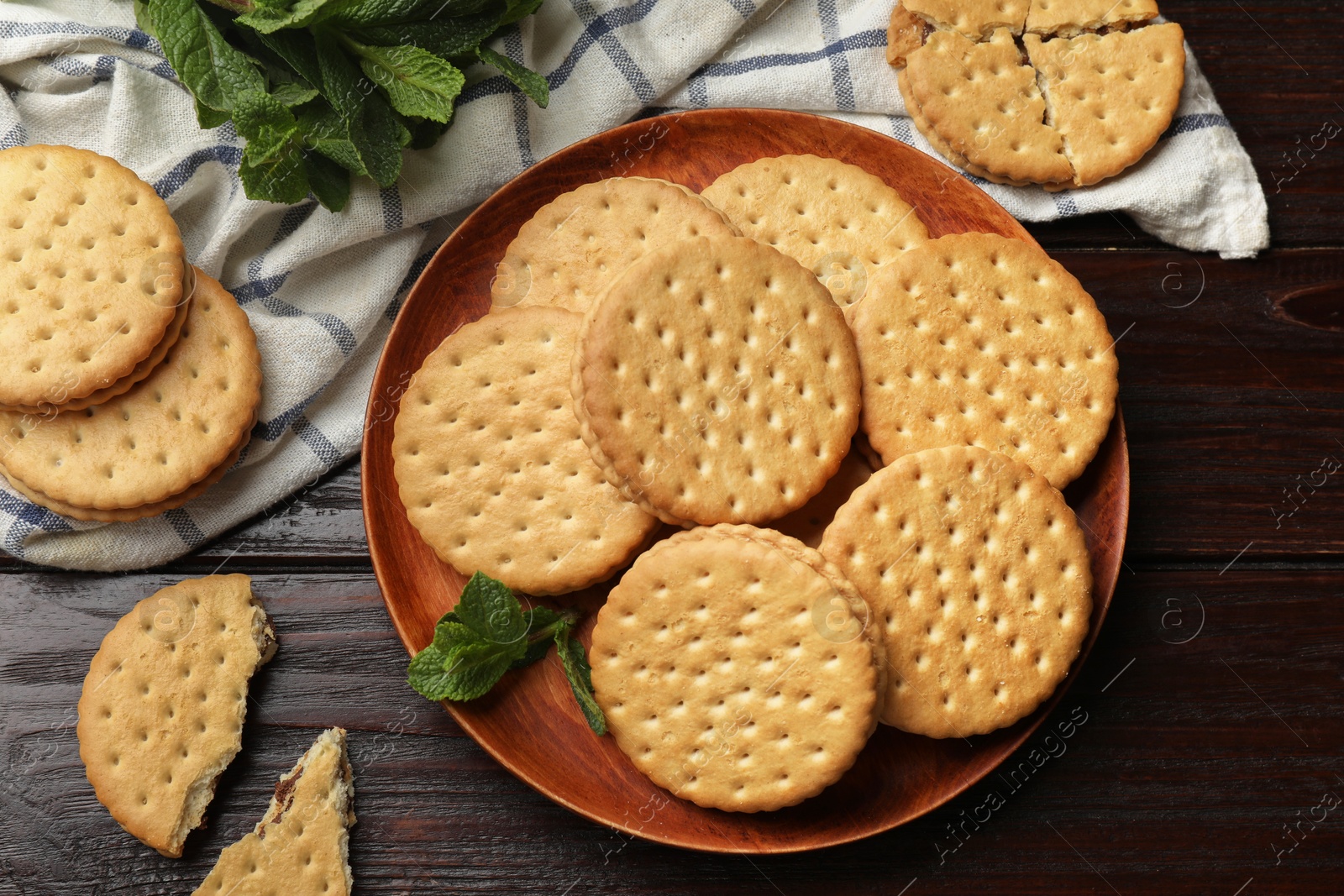 Photo of Tasty sandwich cookies and mint on wooden table, flat lay