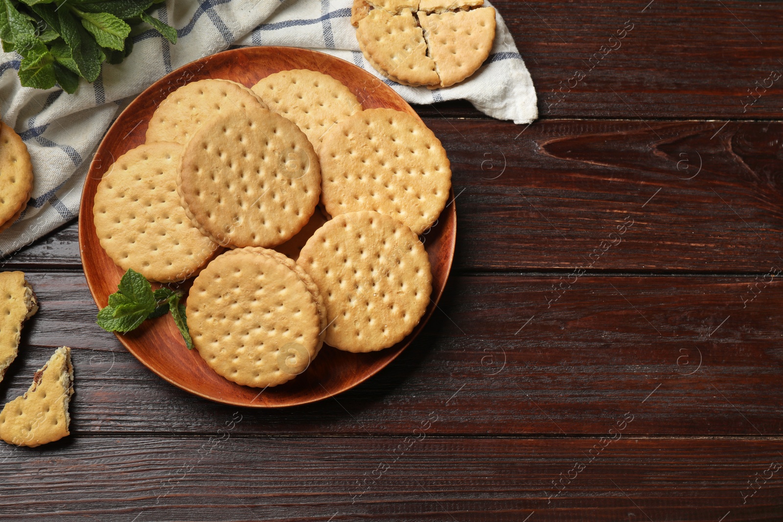 Photo of Tasty sandwich cookies and mint on wooden table, flat lay. Space for text