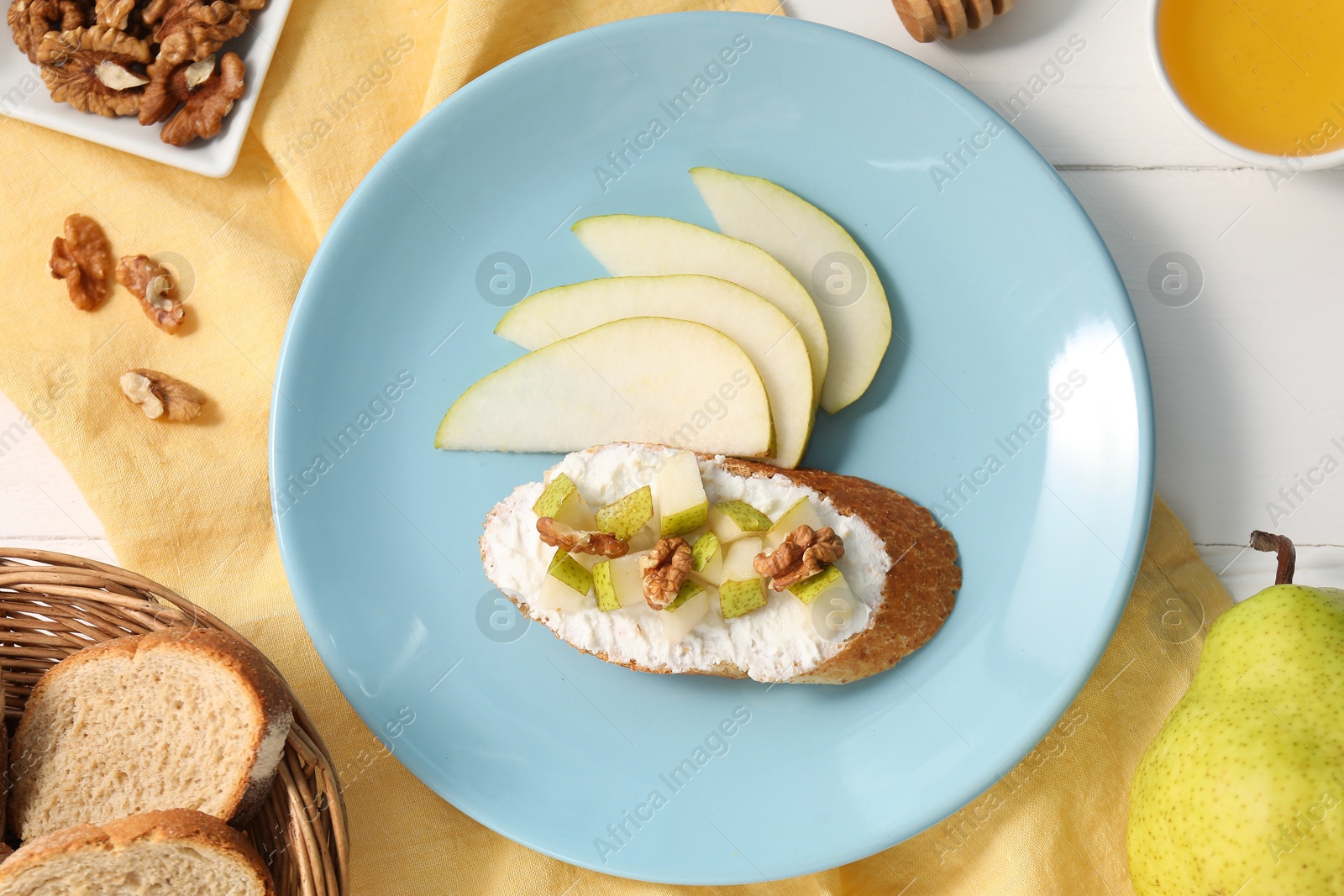 Photo of Delicious ricotta bruschetta with pear and walnut served on white wooden table, flat lay