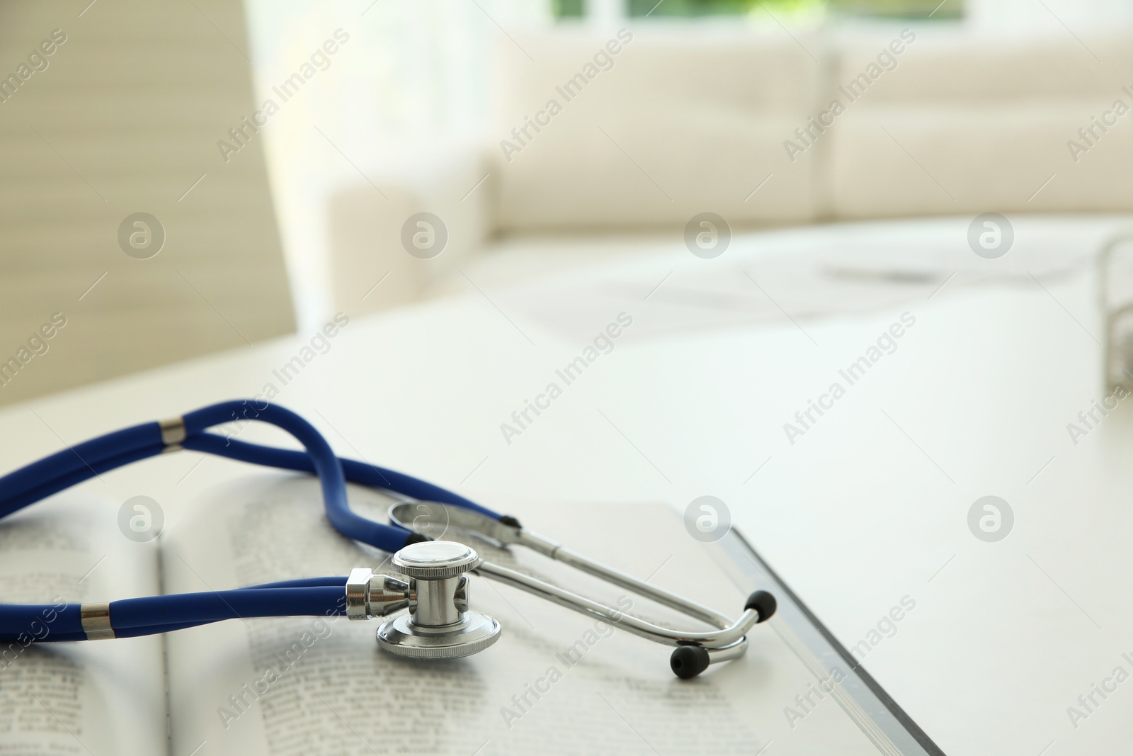 Photo of One new medical stethoscope and book on white table