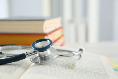 Photo of One new medical stethoscope and books on table, closeup