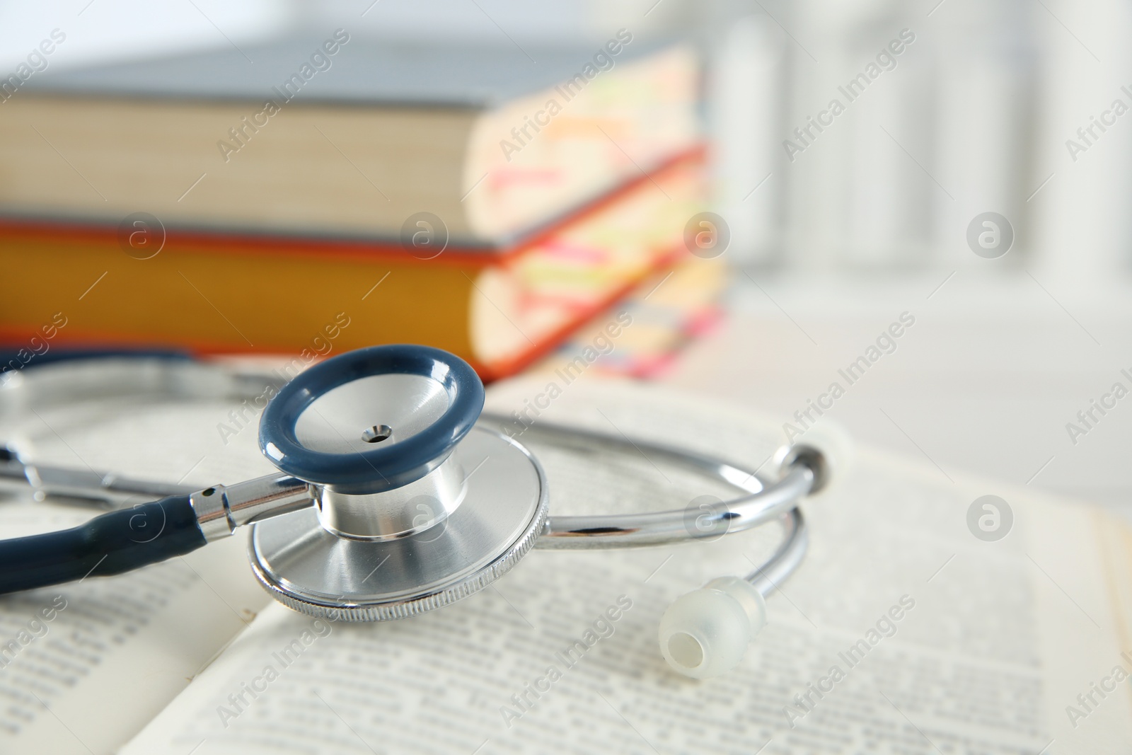 Photo of One new medical stethoscope and books on table, closeup