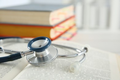 One new medical stethoscope and books on table, closeup