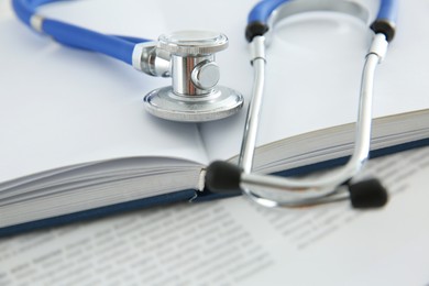 One new medical stethoscope and books on table, closeup