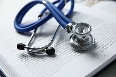 One medical stethoscope and book on table, closeup