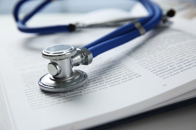 One medical stethoscope and book on white table, closeup