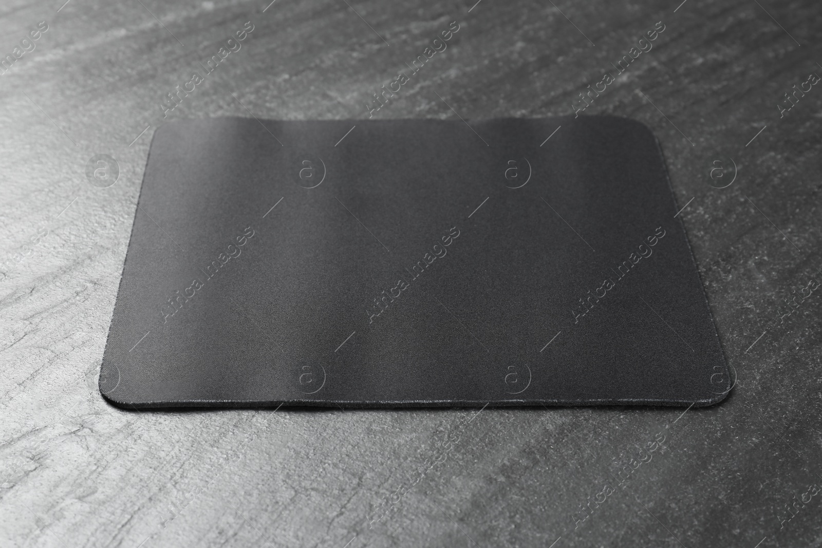 Photo of One mouse pad on black textured table. Space for text