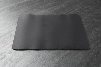 Photo of One mouse pad on black textured table. Space for text