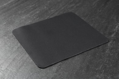 One mouse pad on black textured table. Space for text