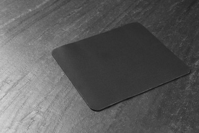 One mouse pad on black textured table. Space for text