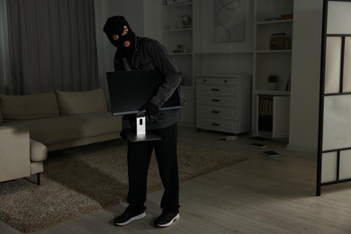 Photo of Thief stealing computer monitor at foreign house. Burglary