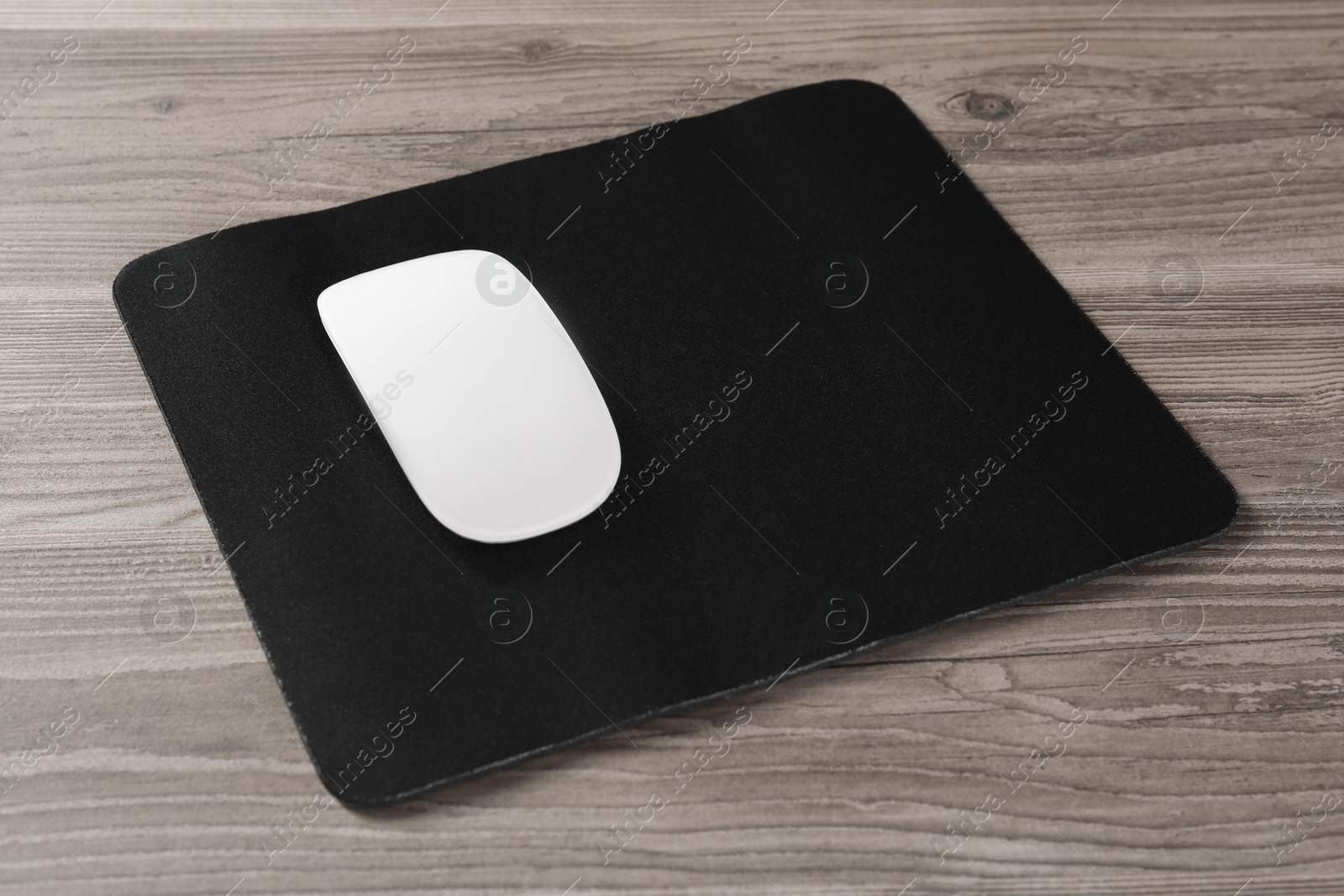 Photo of Wireless mouse and mousepad on wooden table